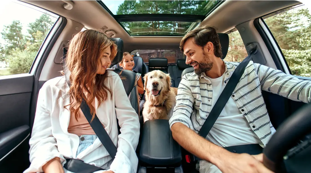 Familia feliz con un perro en el coche